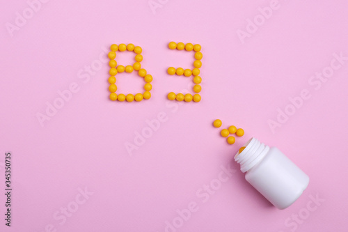 Creative healthcare and medicine concept picture vitamins and capsules on a pink background like the letter B3