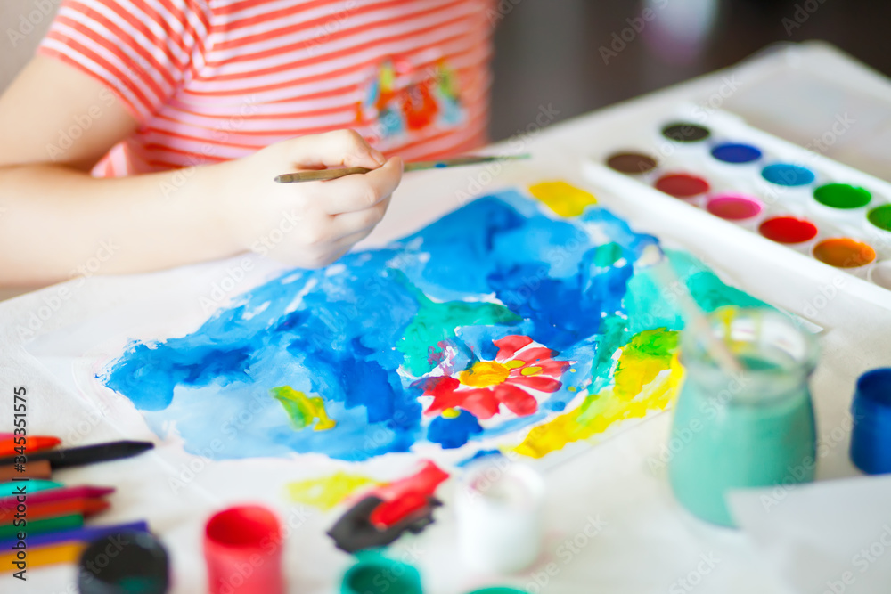 A child draws flower with colored paints on the paper. A child draws flower with colored paints on the paper.