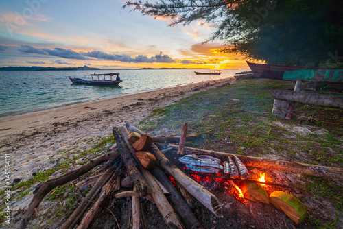 Fish bbq on tropical desert beach. Cooking barbecue with wood fire at sunset, colorful sky on sea, dramatic clouds, getting away, adventure in Indonesia Sumatra Banyak Islands © fabio lamanna