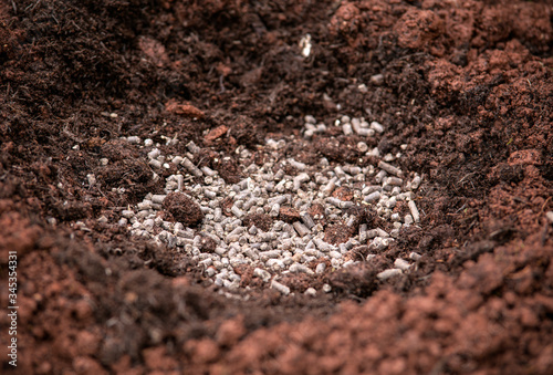 adding chicken manure pellets to soil ground for planting in garden