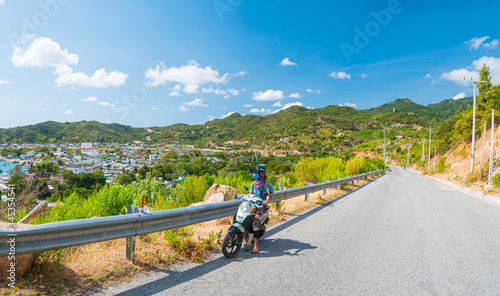 One person riding motorbike on winding road looking at view of gorgeous coast in the Phu Yen province, Nha Trang Quy Nhon, adventure traveling in Vietnam. Unique tropical bay and golden beach.