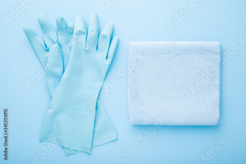 Rag and rubber protective gloves for different surfaces cleaning in kitchen, bathroom and other rooms. Light blue table background. Pastel color. Closeup. Regular cleanup. Top down view.
