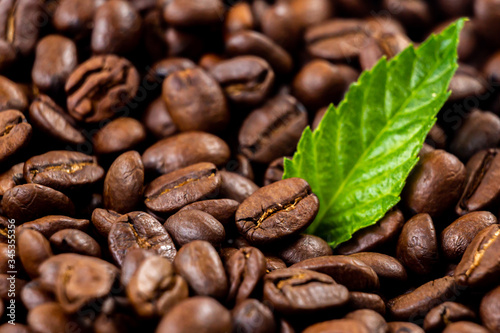 Roasted coffee beans with and green leaves ,isolated in white background