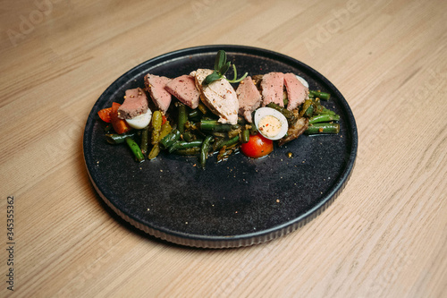 meat with asparagus, tomato, egg on a black grater on a wooden table