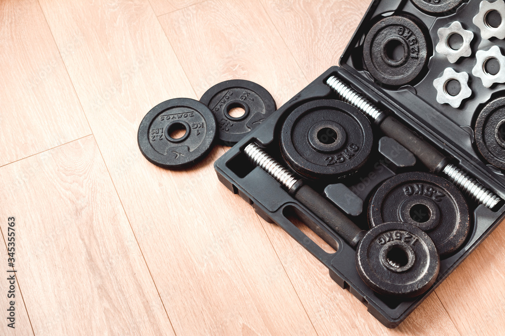 Fototapeta premium a set of dumbbells for sports at home on a wooden floor for the period of isolation. box with dumbbells