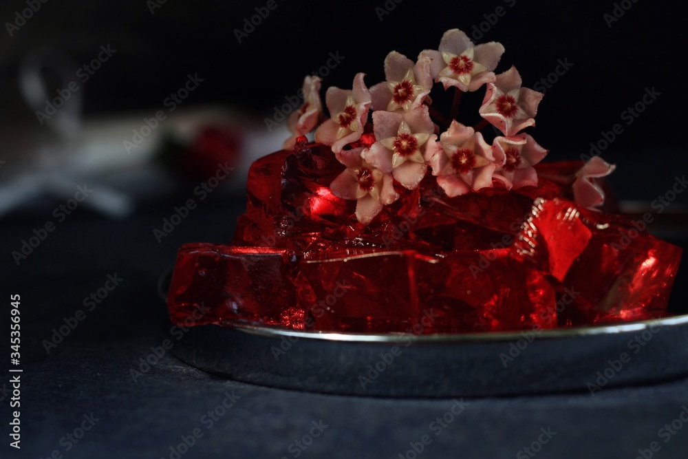 Sweet jelly dessert, design food, creative meals with vanilla flowers in dark mood on black background