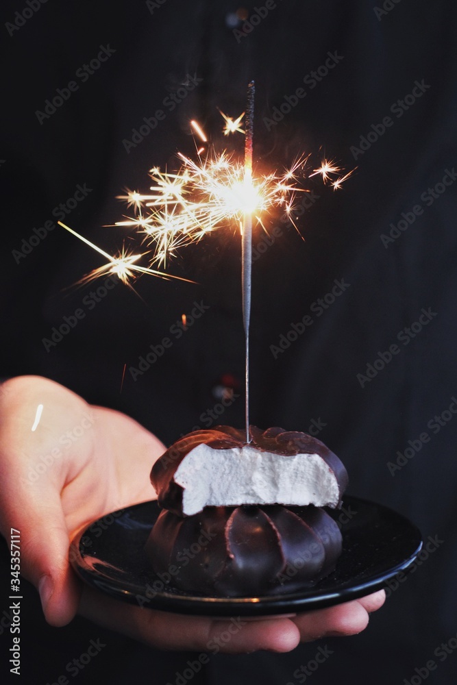 Chocolate marshmallows with sparklers, design food, dark mood on black background