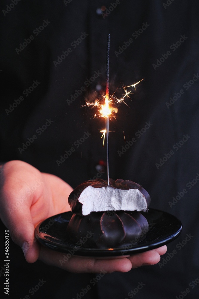 Chocolate marshmallows with sparklers, design food, dark mood on black background