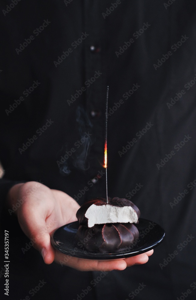 Chocolate marshmallows with sparklers, design food, dark mood on black background