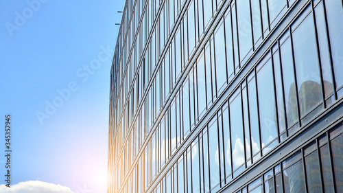 Modern building in the city with sunlight. Glass wall of an office building in the sunlight. Office building window close up with sunrise, reflection and perspective.