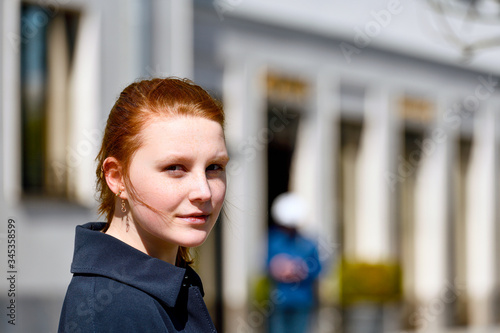 Junges Mädchen mit rötlichem Haar lächelt in die Kamera -Brustbild outdoor, seitlicher Blick photo