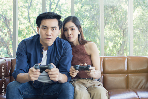 An asian couple is exciting while playing video game together in living room at home
