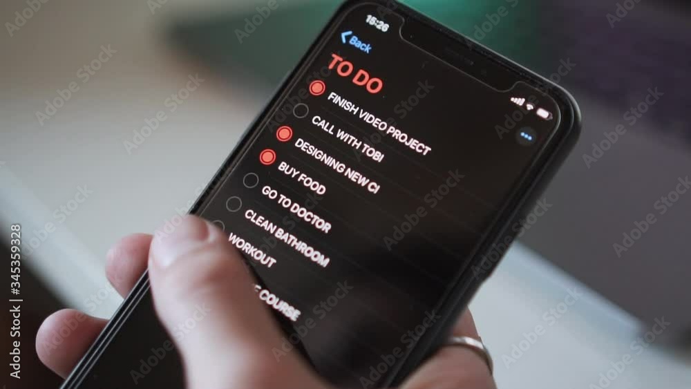 Ticking off point of a to do list on cell phone, close up, slow motion