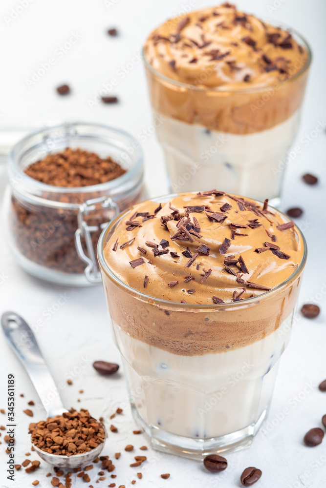 Trendy korean drink Dalgona coffee with ice, garnished with grated chocolate, light gray background, vertical