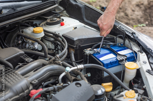 Man fixing car battery with wrench. Replacing car battery.
