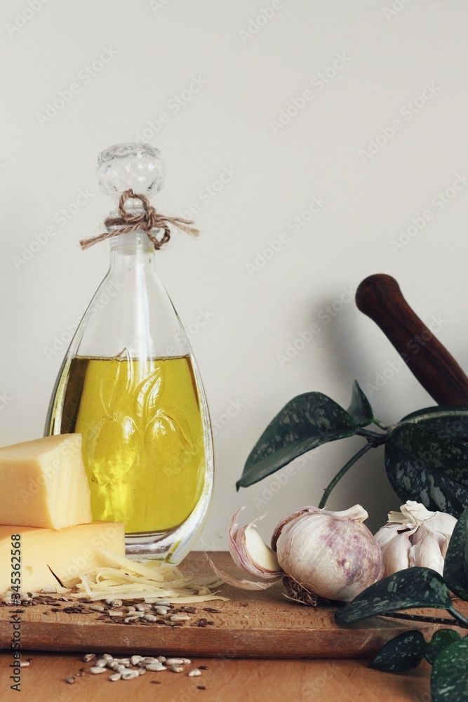Art composition, design food - oil, garlic, spices and cheese on wooden table and white background