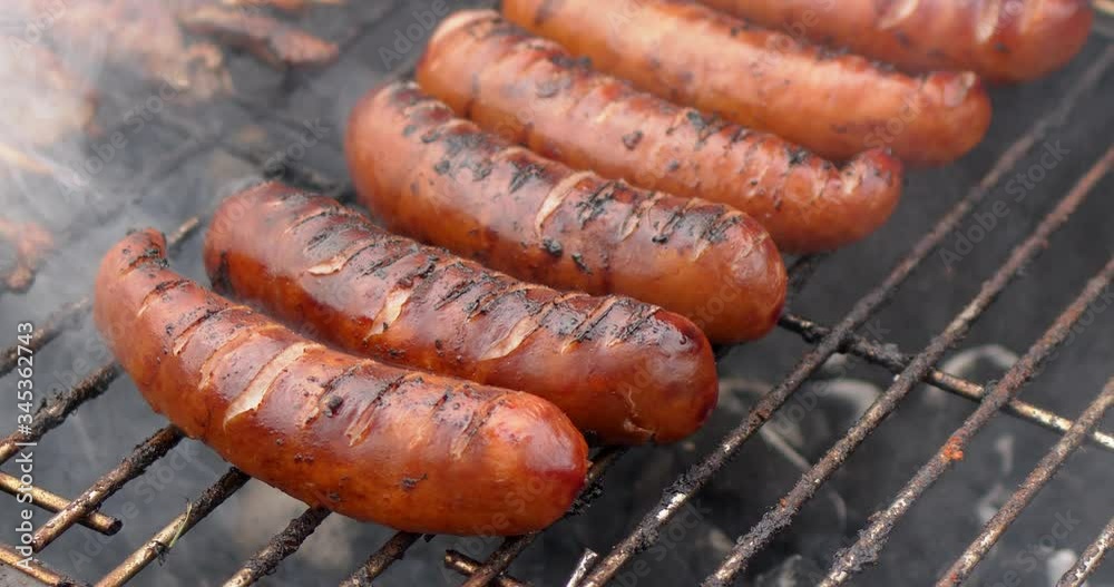 Hot tasty grilled sausages frying on smoking barbecue. Slow motion video Hot tasty grilled sausages frying on smoking barbecue. Slow motion video