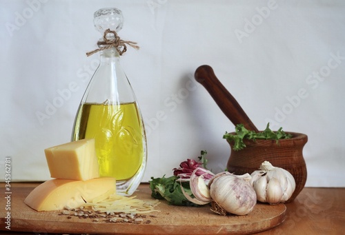 Art composition, design food - oil, garlic, spices and cheese on wooden table and white background