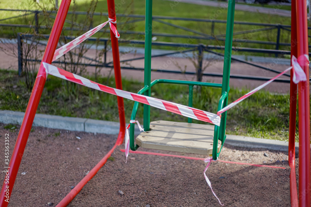 The playground is in quarantine due to the coronavirus pandemic. Warning Red and white ribbons are torn by bad citizens on a swing. The playground is in quarantine due to the coronavirus pandemic. Warning Red and white ribbons are torn by bad citizens on a swing.