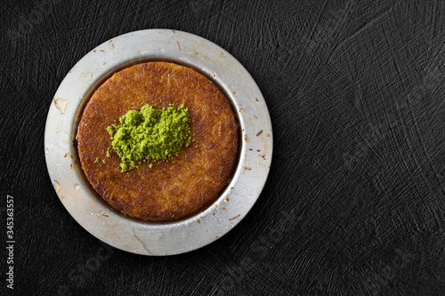 Traditional dessert kunefe with pistachio over black textured background, top view, copy space photo