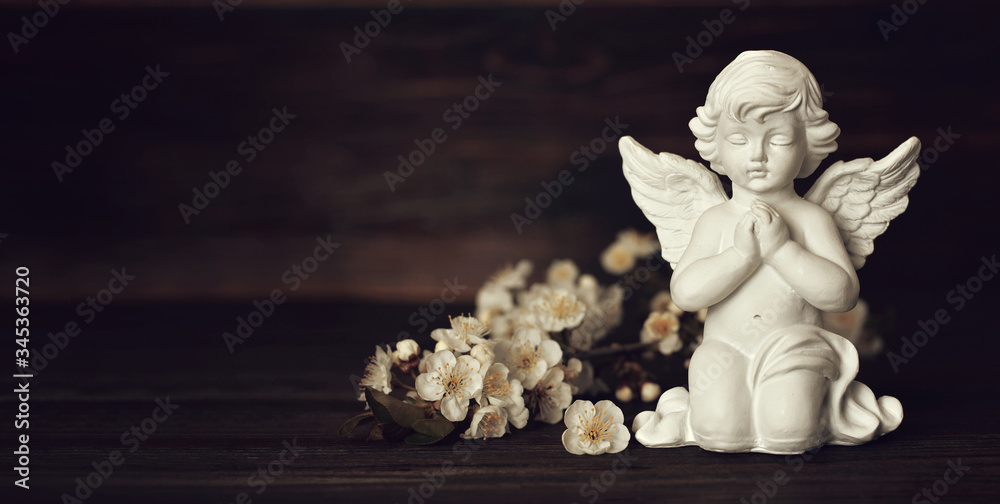Condolence card with guardian angel and white spring flowers on wooden background with copy space Condolence card with guardian angel and white spring flowers on wooden background with copy space