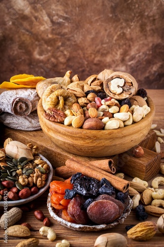 Composition from mix of dried fruits and nuts - symbols of judaic holiday Tu Bishvat. Brown background, vertical format