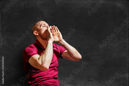 a young man shouts with his hands cupped like a megaphone