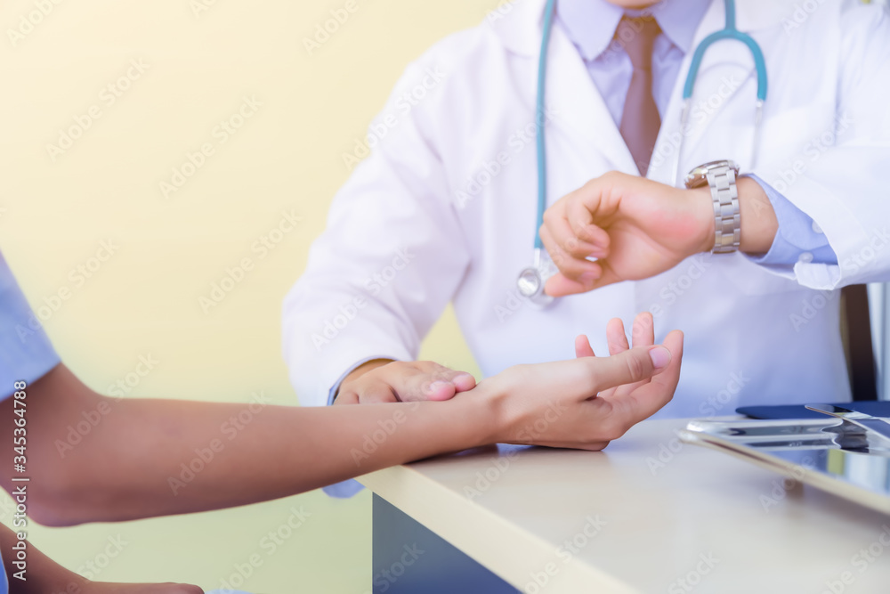 Doctor take patience's pulse by fingers, touch patients wrist. doctor checking time on wristwatch. Working on doctors table in doctor office at medical clinic. General doctor check up patient. Doctor take patience's pulse by fingers, touch patients wrist. doctor checking time on wristwatch. Working on doctors table in doctor office at medical clinic. General doctor check up patient.
