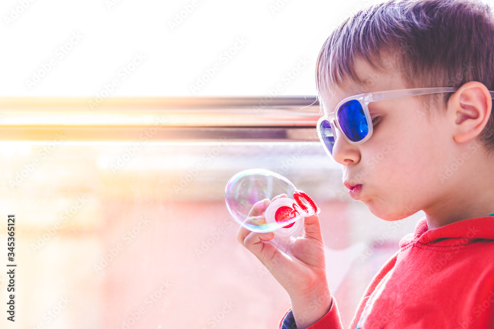blond kid with sunglasses playing with soap bubbles near balcony blond kid with sunglasses playing with soap bubbles near balcony