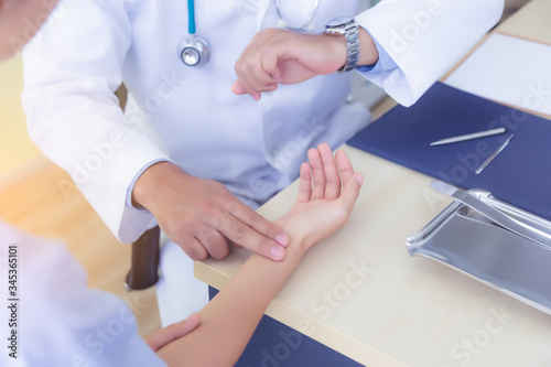 Doctor check patience s pulse by fingers  touch patients wrist. Doctor look at wristwatch  medical checking on doctors table in doctor office at medical clinic. General doctor care patient. healthcare