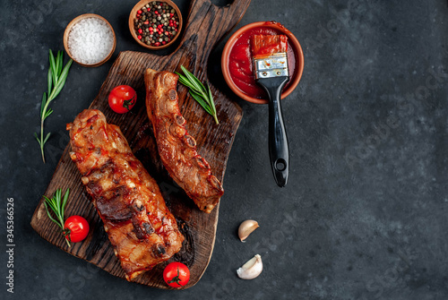 Grilled pork ribs with spices on a cutting board on a stone background with copy space for your text