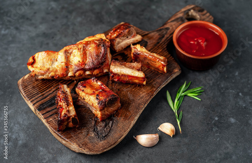 Grilled pork ribs with spices on a cutting board on a stone background