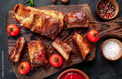 Grilled pork ribs with spices on a cutting board on a stone background