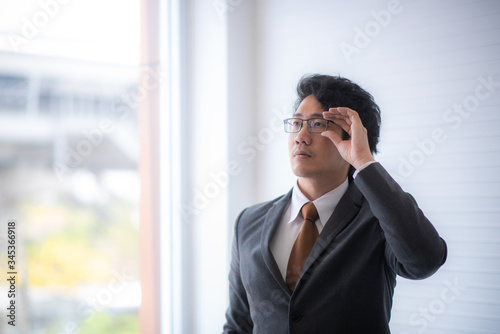 A young Asian businessman in a gray suit is looking out for good vision. Elegant personality of business people