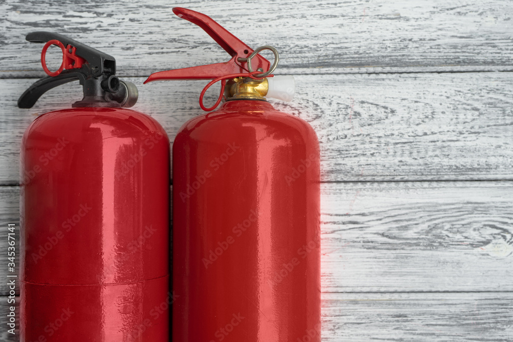 Two red hand extinguishers on a light wooden background. Copy space