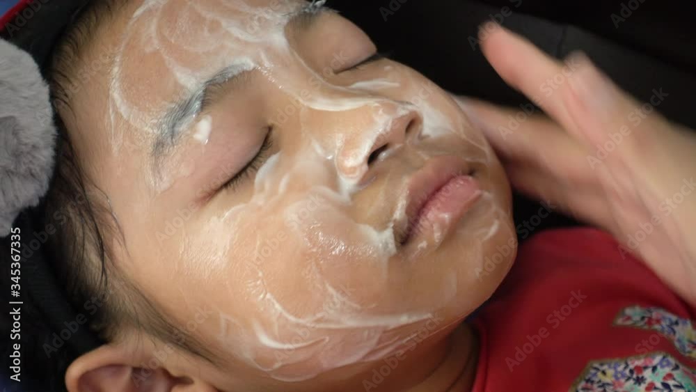 Asian child girl is applying honey and yogurt to baby face by her mother Asian child girl is applying honey and yogurt to baby face by her mother
