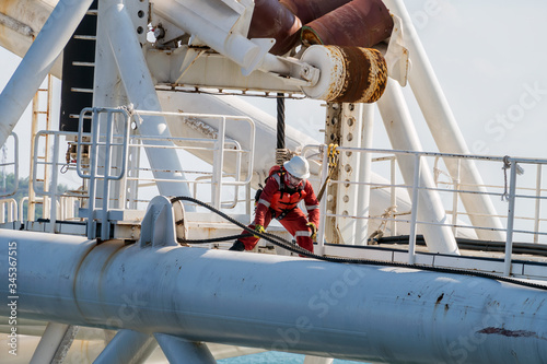 Riggers preparing sling on a derrick lay barge's stinger after its intallation during mobilization at a port