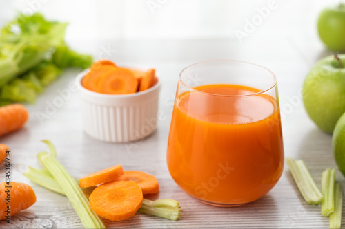 Glass with carrot juice, celery and green apple on the table.