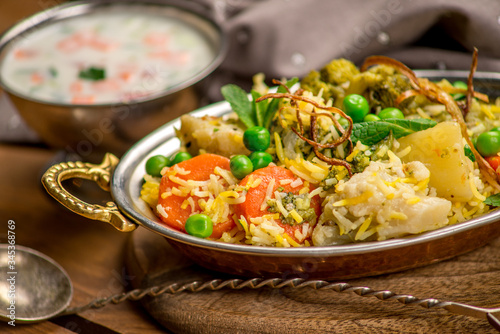 Biryani indian cuisine in bowl with vegetables rice traditional wooden board texture