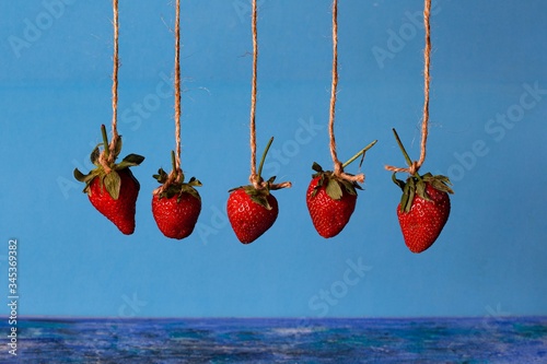 pendulum from berries of red strawberries on a blue background