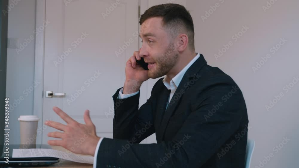 Positive entrepreneur businessman talking mobile phone emotionally at home office. Business discussion by phone, workflow. Positive entrepreneur businessman talking mobile phone emotionally at home office. Business discussion by phone, workflow.