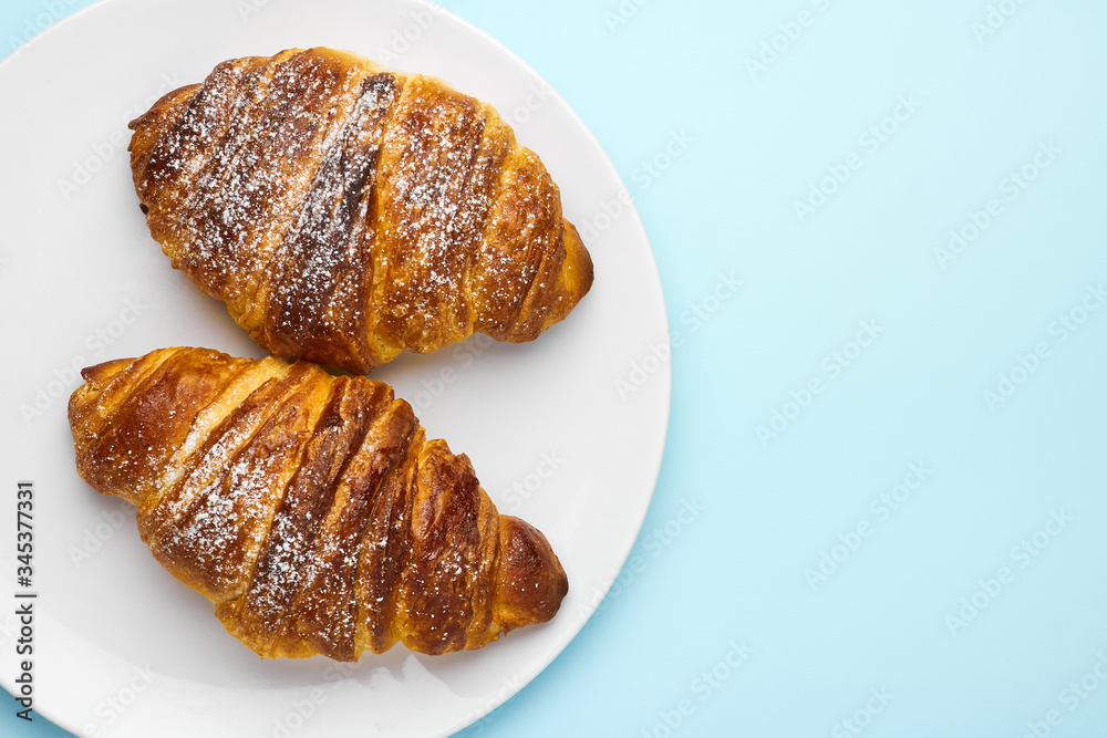 Freshly baked italian croissants on a white plate on the blue background with copy space. Concept of advertisement of traditional pastry. Freshly baked italian croissants on a white plate on the blue background with copy space. Concept of advertisement of traditional pastry.