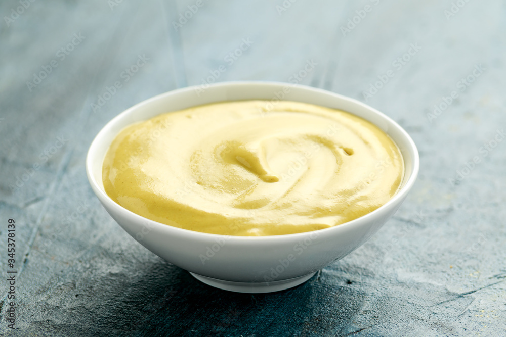 Dijon mustard in white bowl on rustic background Dijon mustard in white bowl on rustic background