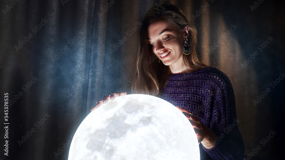 Naklejka premium Portrait of dreaming woman with the bright round full shining moon at night time