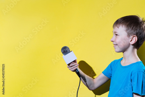 Little happy journalist with microphone isolated on yellow color background.