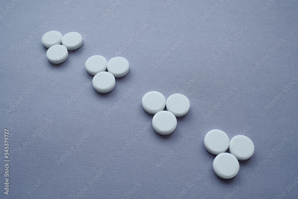 Round medicinal pills in the form of three triangles arranged in a row on a dark purple background, isolate. Round medicinal pills in the form of three triangles arranged in a row on a dark purple background, isolate.