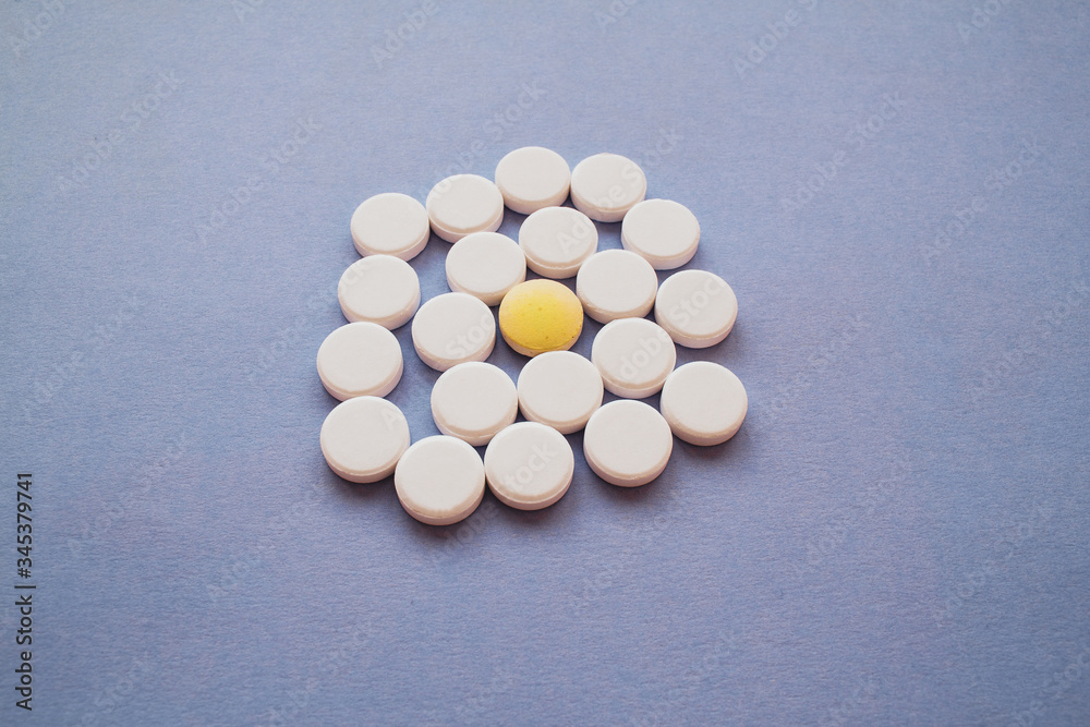 Round white pills and yellow one on a purple background in the middle of shot Round white pills and yellow one on a purple background in the middle of shot