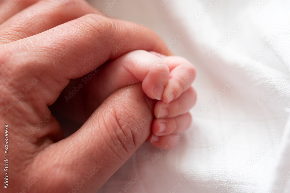 Closeup of a baby's hand holding father's finger against white background. Close-up of beautiful sleeping baby girl. Newborn baby girl, asleep on a blanket. Selective focus. Closeup photo. Closeup of a baby's hand holding father's finger against white background. Close-up of beautiful sleeping baby girl. Newborn baby girl, asleep on a blanket. Selective focus. Closeup photo.