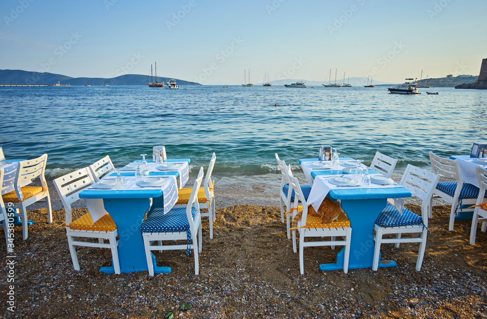 Cute chairs and table on the beach at seaside restaurant in Bodrum