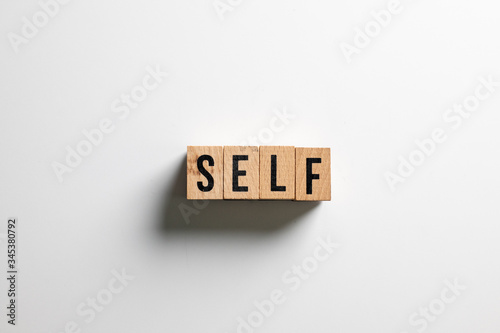 " self " text made of wooden cube on White background.